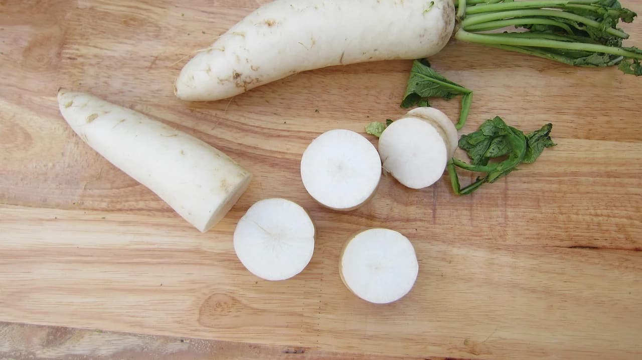 Daikon radish whole and sliced into rounds on a wooden cutting board