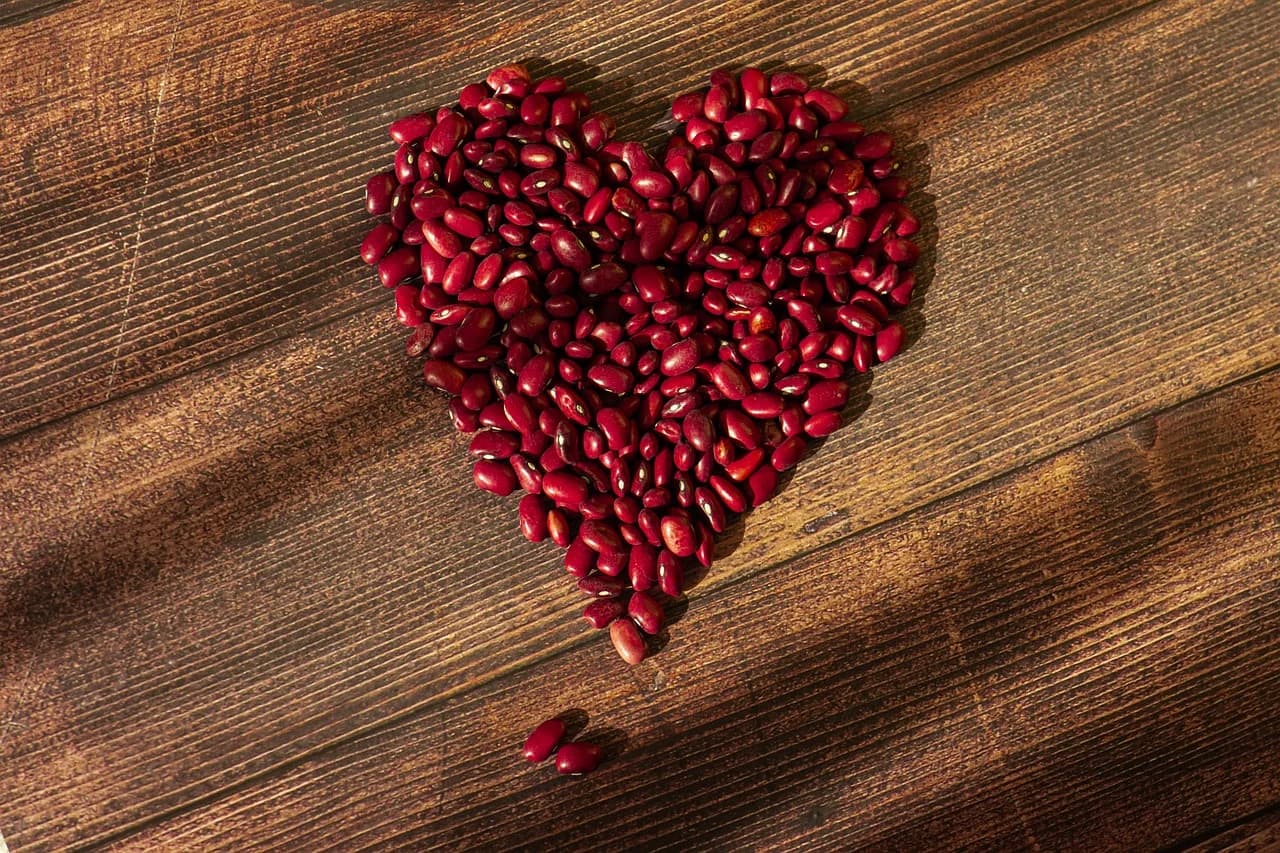 Kidney Bean dried red seeds arranged in a heart shape on a rustic wooden surface
